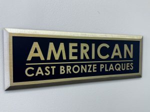 Sign displaying 'American Cast Bronze Plaques' in bold lettering with a gold and blue color scheme.