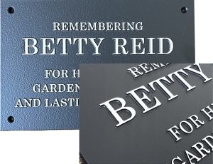 Bronze plaque with engraved text remembering Betty Reid for her gardening and lasting contributions.