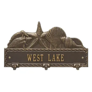 Bronze wall plaque with sea shell design and hooks labeled 'WEST LAKE'.