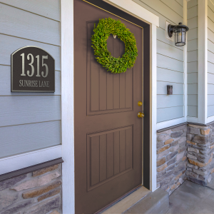 Brown door with a decorative wreath and house number plaque at 1315 Sunrise Lane.