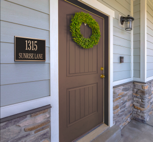 Brown front door with a green wreath and a house number plaque reading '1315 Sunrise Lane'.