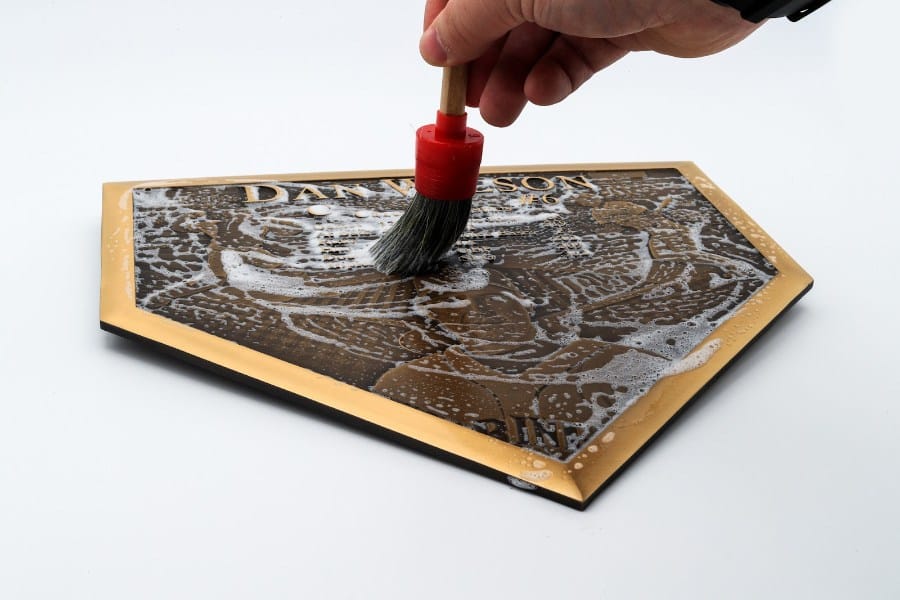 Bronze plaque being cleaned with a soft-bristled brush