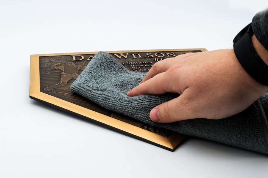 Hand cleaning a bronze plaque with a soft cloth